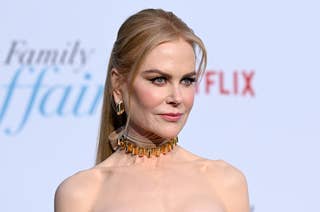 Nicole Kidman on a red carpet wearing a strapless dress and a statement choker necklace, posing for 