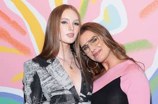 Grier Henchy in a patterned blazer poses with actress Brooke Shields in a pink and black outfit, against a colorful background at an event