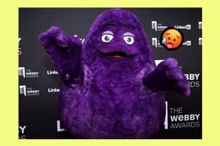 Grimace mascot holds its arms out to the camera with a superimposed sweating emoji next to him